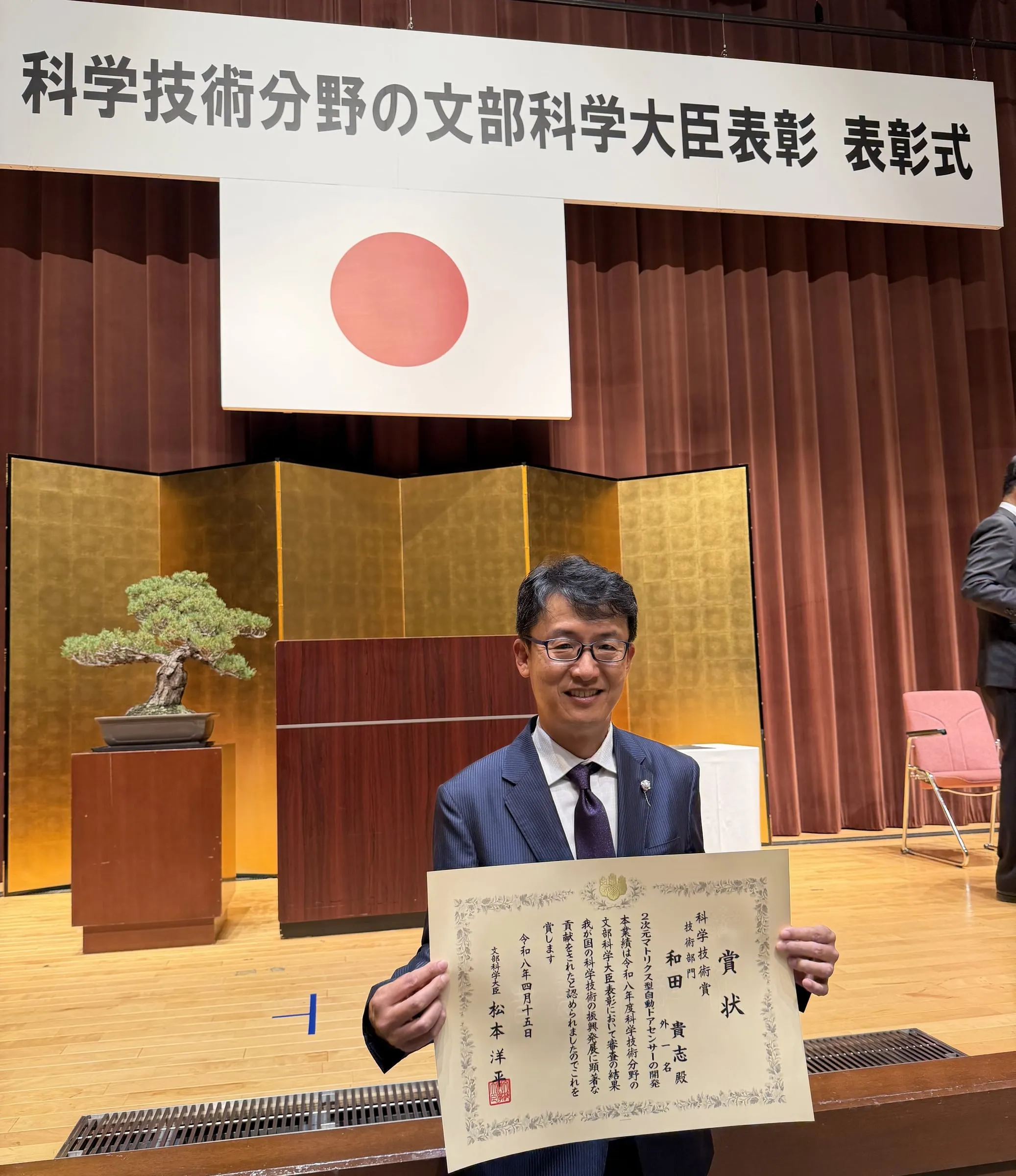 文部科学大臣表彰の表彰式で賞状を持つ受賞者