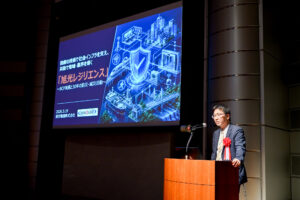BCAOアワード2025で、旭光電機によるBCAOの取り組みを登壇者の社長がステージで発表している様子